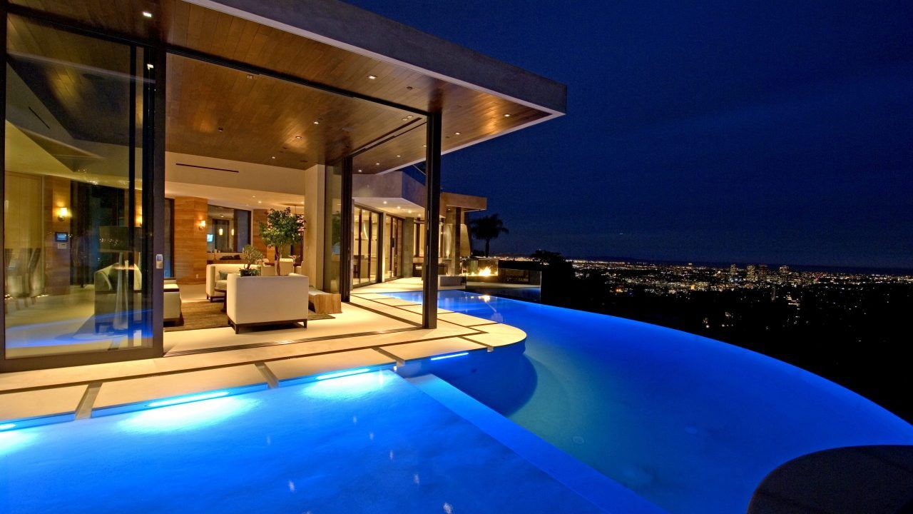 Infinity pool outside patio of a beautiful home with an amazing view of the city at night | modern architecture firm in Los Angeles | Dean Larkin Design