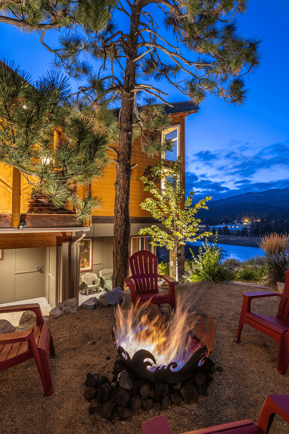 Eagle Lake Project - Fire in firepit with view of side of house and water - Dean Larkin Design